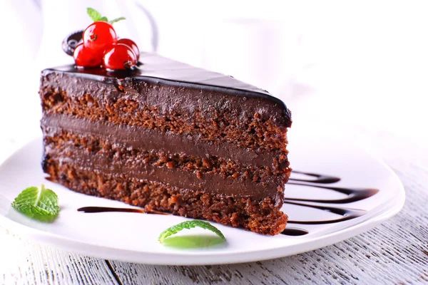 Delicioso bolo de chocolate na placa na mesa no fundo claro — Fotografia de Stock