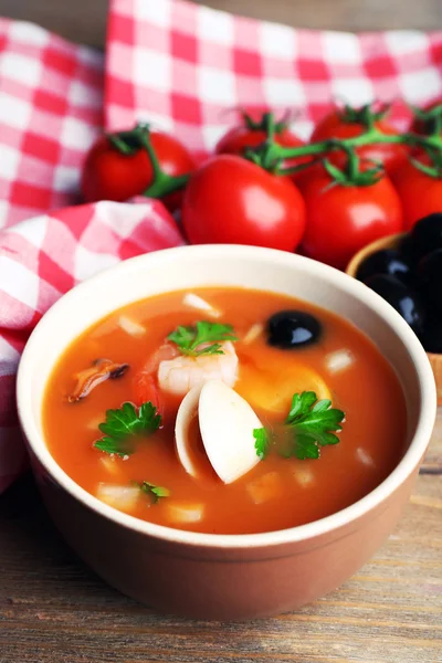 Smakfull suppe med reker, blåskjell, tomater og svarte oliven i bolle på trebakgrunn – stockfoto