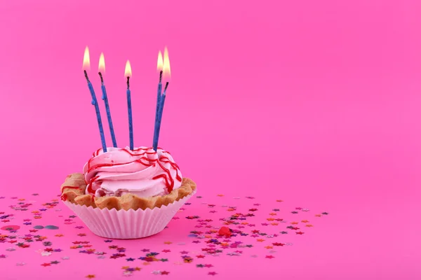 Birthday cup cake with candles and colorful stars on pink background — Stock Photo, Image