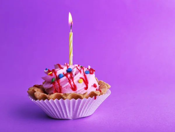 Gâteau avec bougie d'anniversaire sur fond violet — Photo