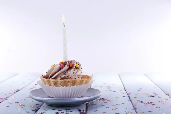 Bolo de xícara de aniversário com vela com brilhos na placa na tabela de madeira da cor e fundo claro — Fotografia de Stock