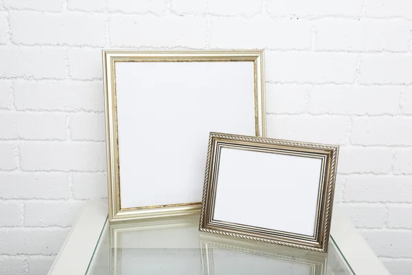 Photo frames on coffee table on brick wall background — Stock Photo, Image