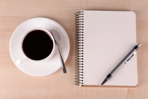 Tasse Kaffee auf Untertasse mit Notizbuch und Stift auf Holztischhintergrund — Stockfoto