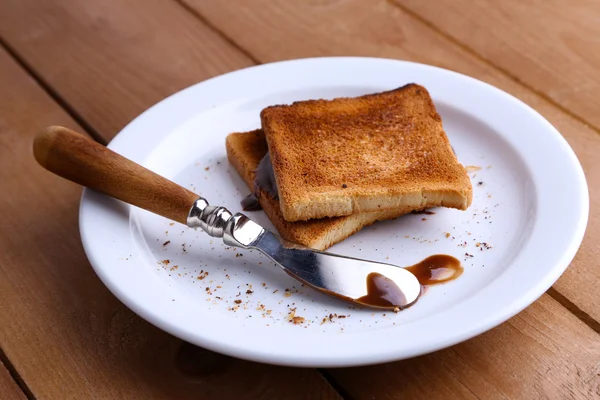 Plaka üzerinde çikolata ahşap masa arka plan üzerine bıçakla ekmeğine tost — Stok fotoğraf