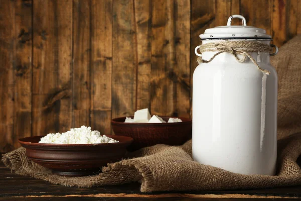 Milk can with cottage cheese on rustic wooden background — Stock Photo, Image
