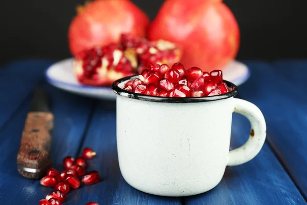 Juicy ripe pomegranate on wooden table, on dark background — Stock Photo, Image