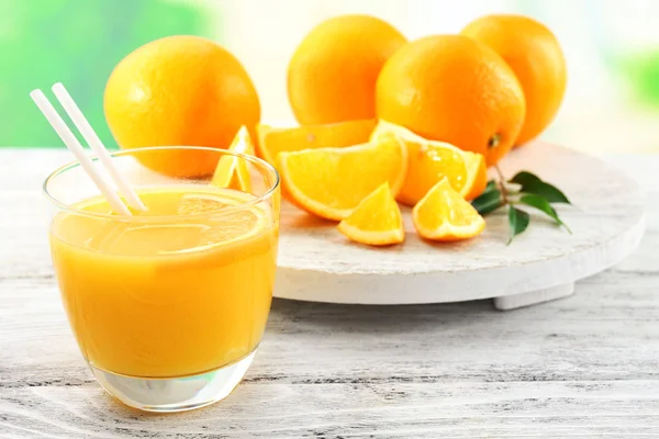 Verre de jus d'orange avec paille et tranches sur fond de table en bois — Photo