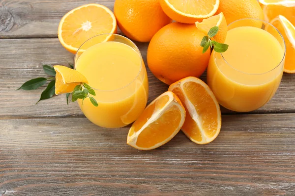 Vaso de zumo de naranja y rodajas sobre fondo de mesa de madera —  Fotos de Stock