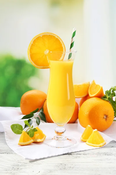 Bardak portakal suyu saman ve ahşap masa ve parlak arka plan dilimleri ile — Stok fotoğraf