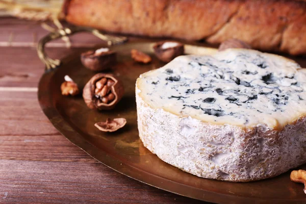 Blue cheese with nuts, baguette and hay on metal tray and wooden table background — Stock Photo, Image