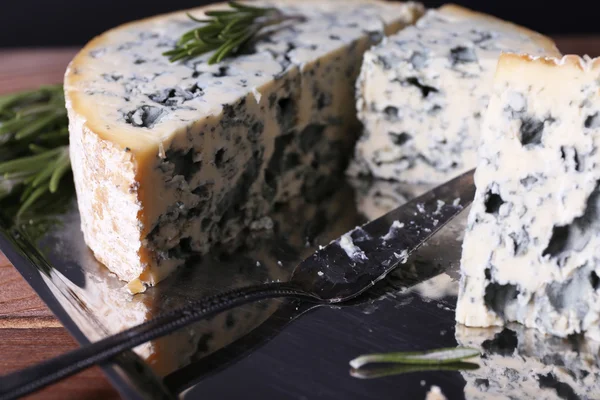 Blue cheese with sprigs of rosemary and blade on metal tray and wooden table background — Stock Photo, Image