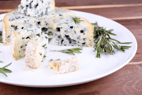 Queijo azul com raminhos de alecrim sobre fundo placa de madeira — Fotografia de Stock