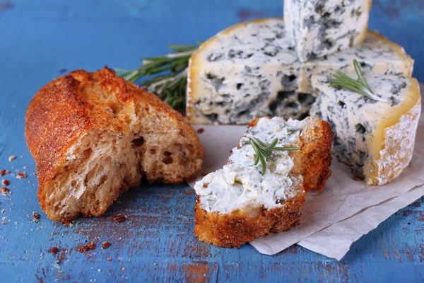 Mavi peynir dal biberiye ve kağıt ve renkli ahşap masa arka plan üzerine ekmek ile — Stok fotoğraf