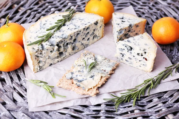 Blue cheese with sprigs of rosemary and oranges on wicker mat background — Stock Photo, Image