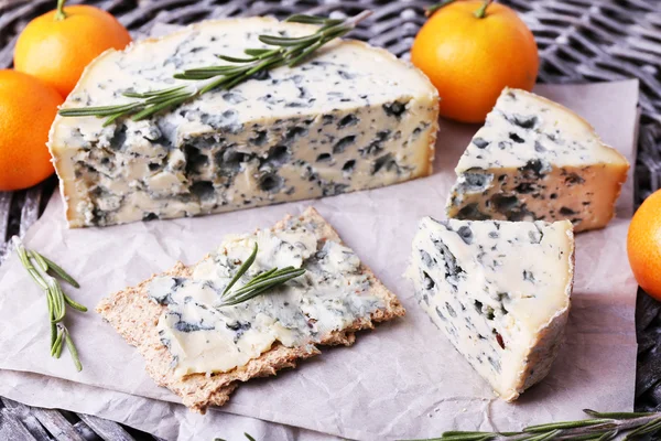 Blue cheese with sprigs of rosemary and oranges on wicker mat background — Stock Photo, Image