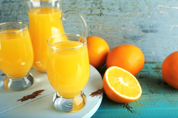 Glass of orange juice with slices on color wooden background — Stock Photo, Image