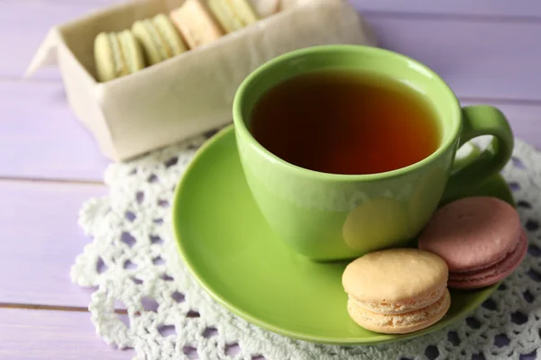 Kolorowe makaroniki filiżankę herbaty na drewniane tła — Zdjęcie stockowe