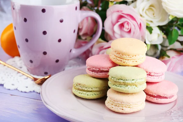 Bunte Makronen mit Tasse Tee auf hölzernem Hintergrund — Stockfoto