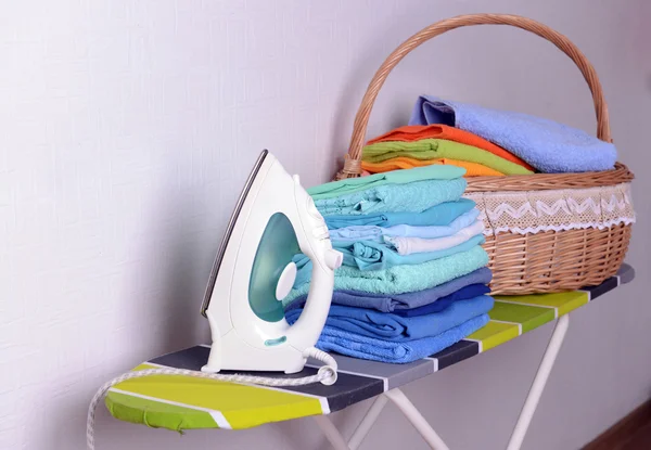 Ironing board with laundry on light background — Stock Photo, Image