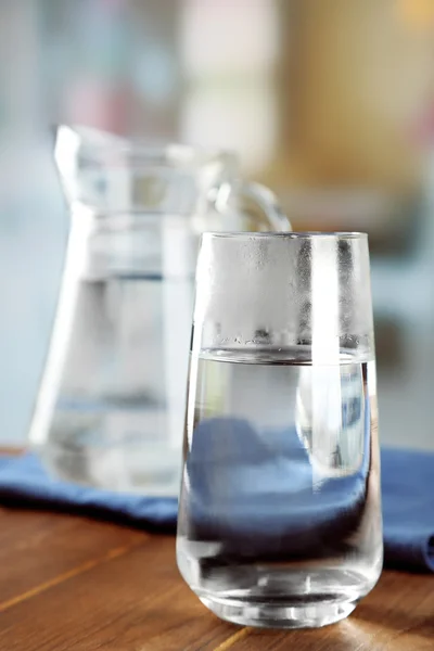 Bicchiere di acqua ghiacciata con tovagliolo sul tavolo di legno e sfondo sfocato chiaro — Foto Stock