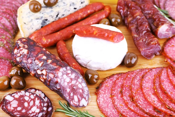 Assortment of smoked sausages and cheese on wooden cutting board background — Stock Photo, Image