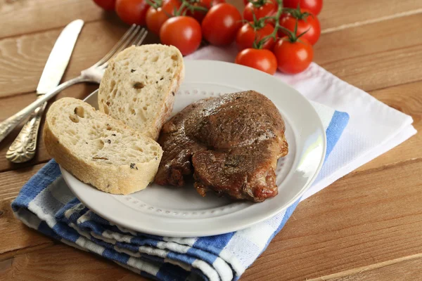 Stekt kött och grönsaker på tallriken, på träbord bakgrund — Stockfoto