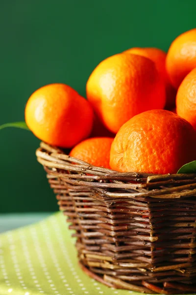 Mandarins maduros frescos na cesta de vime, na mesa de madeira, no fundo da cor — Fotografia de Stock