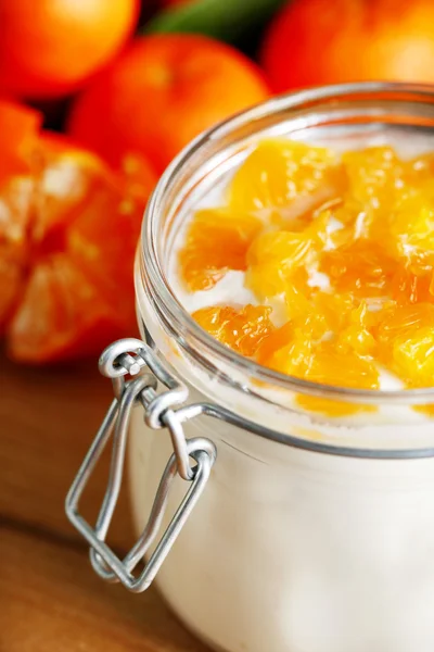 Dessert au lait savoureux avec des morceaux de mandarine frais dans un bocal en verre, sur fond de bois — Photo