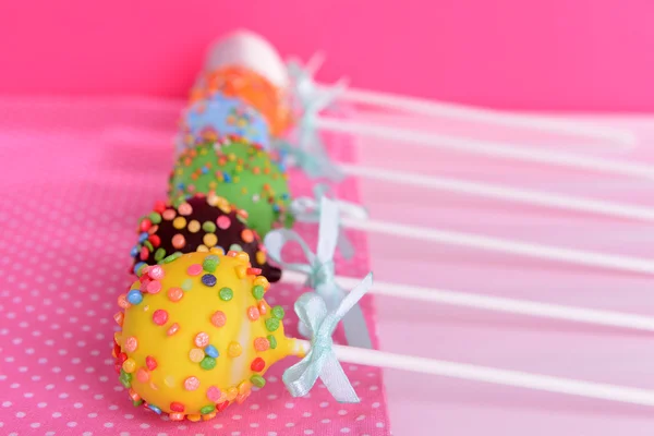 Söta cake pops på tabellen på rosa bakgrund — Stockfoto