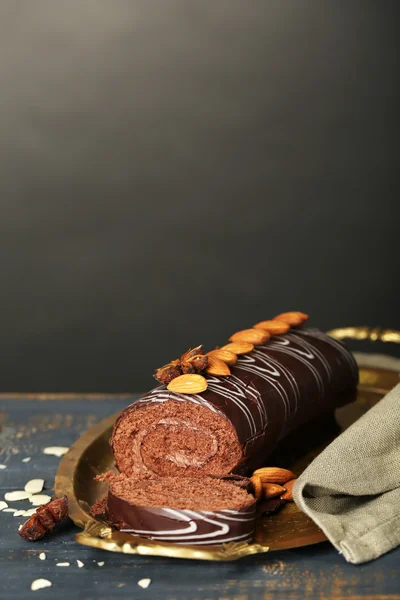 Délicieux gâteau roulé sur table en bois, sur fond sombre — Photo