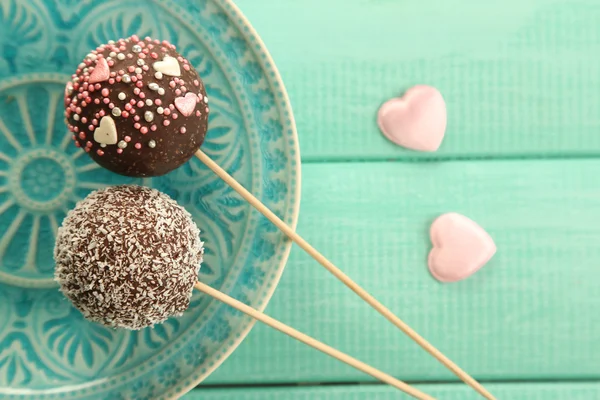 Tasty cake pops on plate, on wooden table — Stock Photo, Image