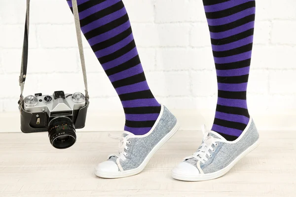 Flicka i sneakers med retro fotokamera i rum — Stockfoto