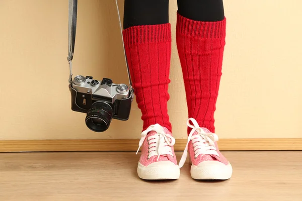 Girl in sneakers with retro photo camera in room — Stock Photo, Image