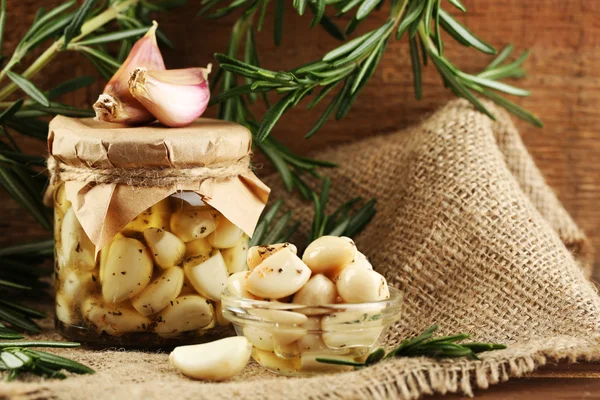 Canned garlic in glass jar on wooden background — Stock Photo, Image