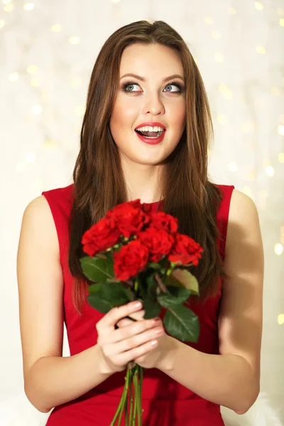 ライトの背景に赤いバラの花束を持つ少女の笑みを浮かべてください。 — ストック写真