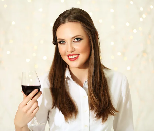 Улыбающаяся девушка с бокалом вина на фоне огней — стоковое фото
