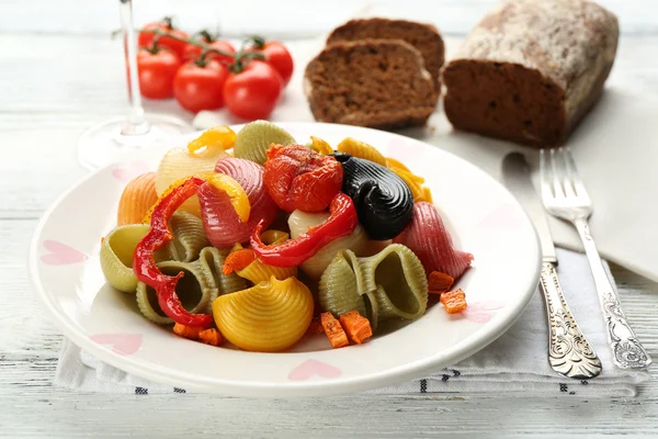 Massa multicolorida saborosa com pimenta, cenoura e tomate sobre fundo de mesa de madeira — Fotografia de Stock