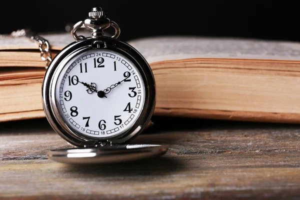 Ezüst zseb-órát, és a fából készült asztal könyv — Stock Fotó