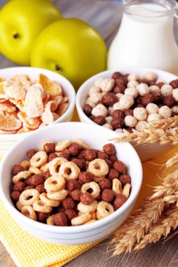 Çeşitli tatlı hububat seramik kase, meyveler ve peçete, renk ahşap arka plan üzerinde süt ile sürahi