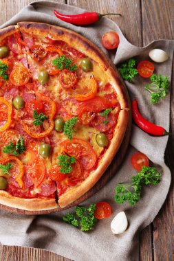 Sosis ve sebze çuval bezi kumaş ve ahşap masa arka plan üzerinde lezzetli pizza