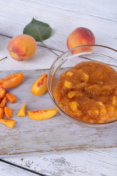 Tasty peach jam with fresh peaches on wooden table — Stock Photo, Image