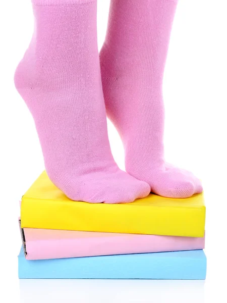Fille en chaussettes colorées debout sur un tas de livres isolés sur blanc — Photo