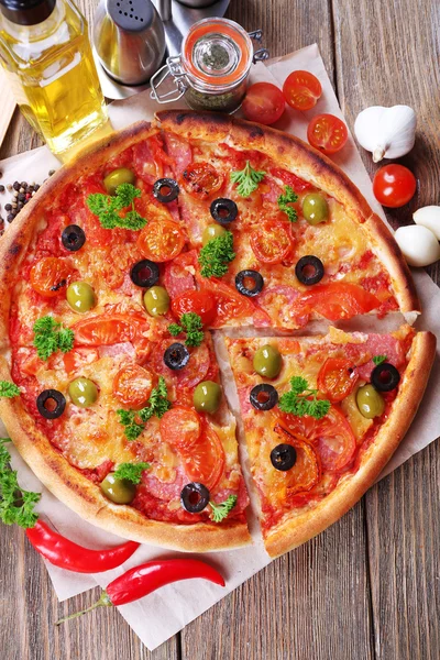 Вкусная пицца с колбасой, овощами и перцем чили на фоне деревянного стола — стоковое фото