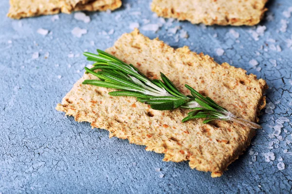 Crispbread with salt and sprigs of rosemary on color wooden table background — Stock Photo, Image