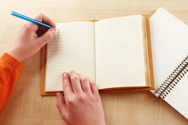 Kvinnlig hand med penna, anteckningsboken och dagbok på träbord bakgrund — Stockfoto