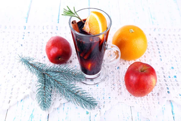 Roodgloeiende glühwein met vruchten en tak van kerstboom op servet, op houten oppervlak achtergrond — Stockfoto