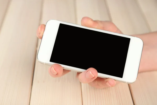 Hand met behulp van slimme mobiele telefoon op houten tafel achtergrond — Stockfoto