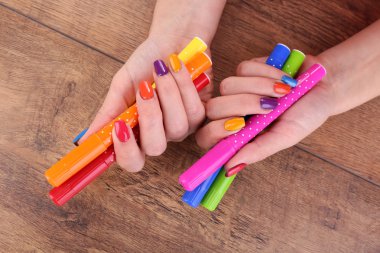 Ahşap arka plan üzerinde işaretçileri olan çok renkli kadın manikür