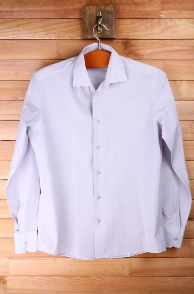 Manliga skjorta på galge på trävägg bakgrund — Stockfoto