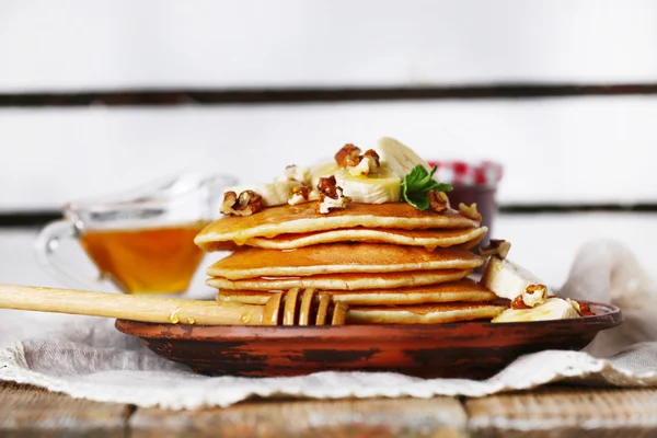 Pilha de panquecas com hortelã, nozes e fatias de banana na mesa com tecido em pranchas de madeira fundo — Fotografia de Stock